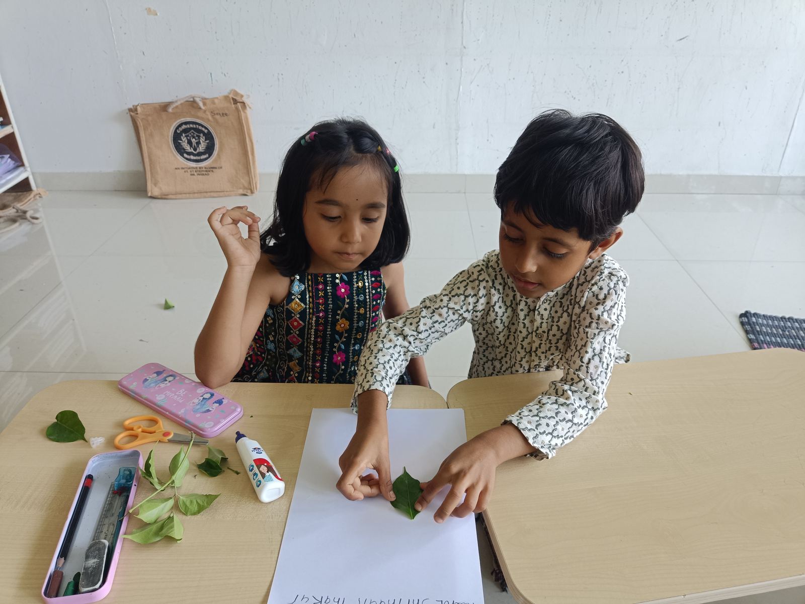 Two children making a leaf card together