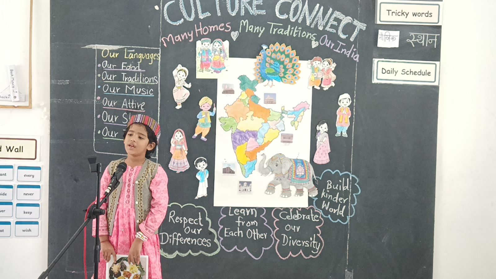 A girl in pink speaks into a microphone in front of the Culture Connect board