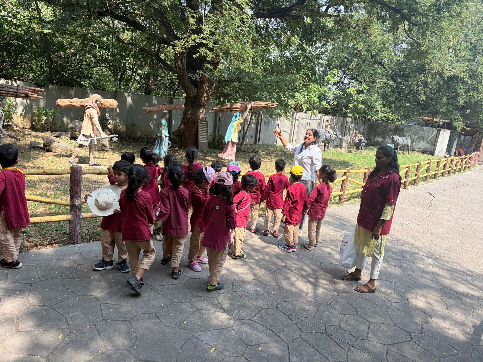Neev children in maroon walk along a path under a big tree